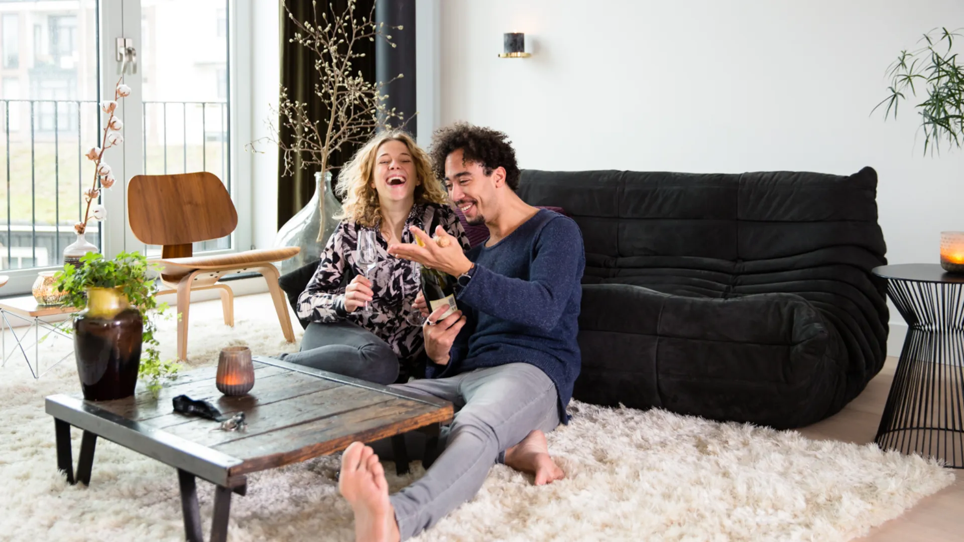 Personen zitten voor de bank op de grond en lachen samen