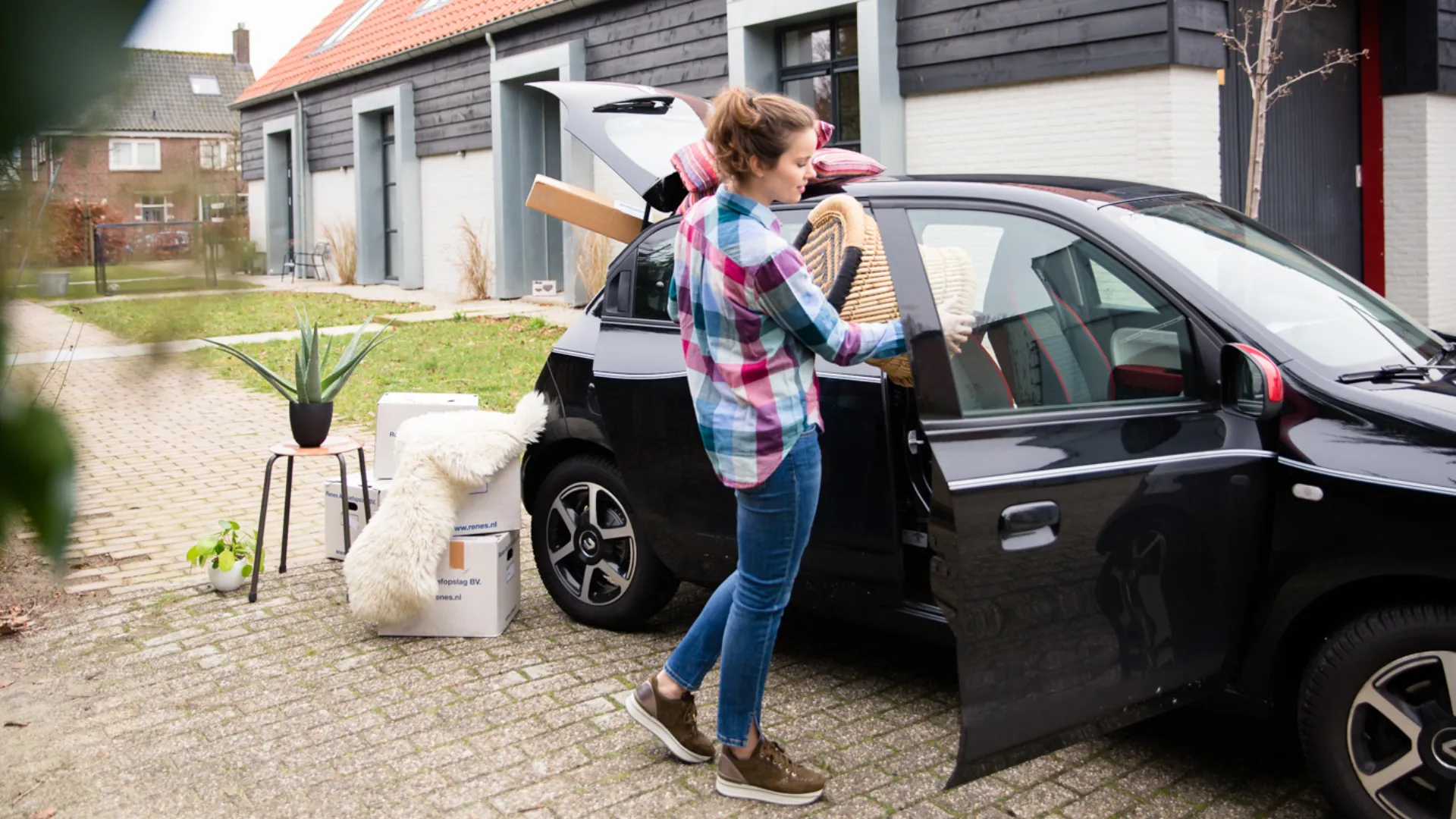 Persoon zet doos met spullen in auto