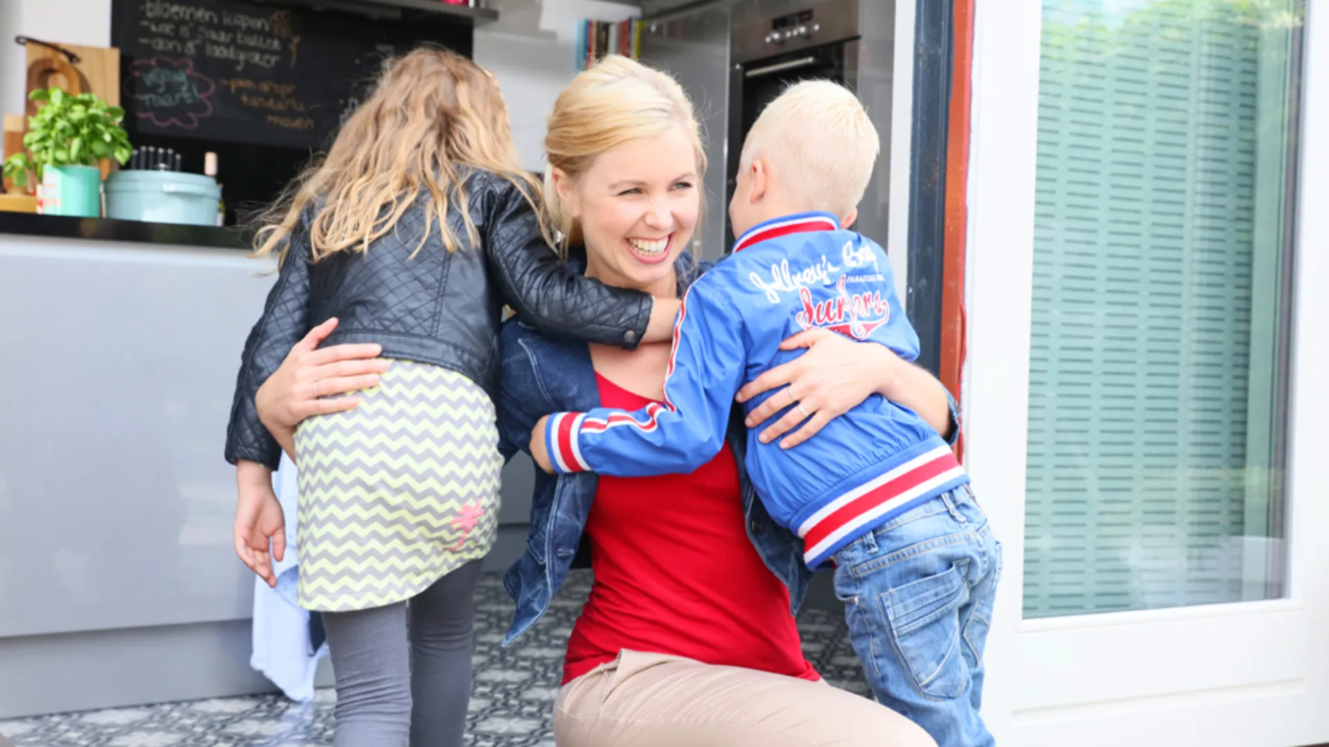 Persoon geeft twee kinderen een knuffel