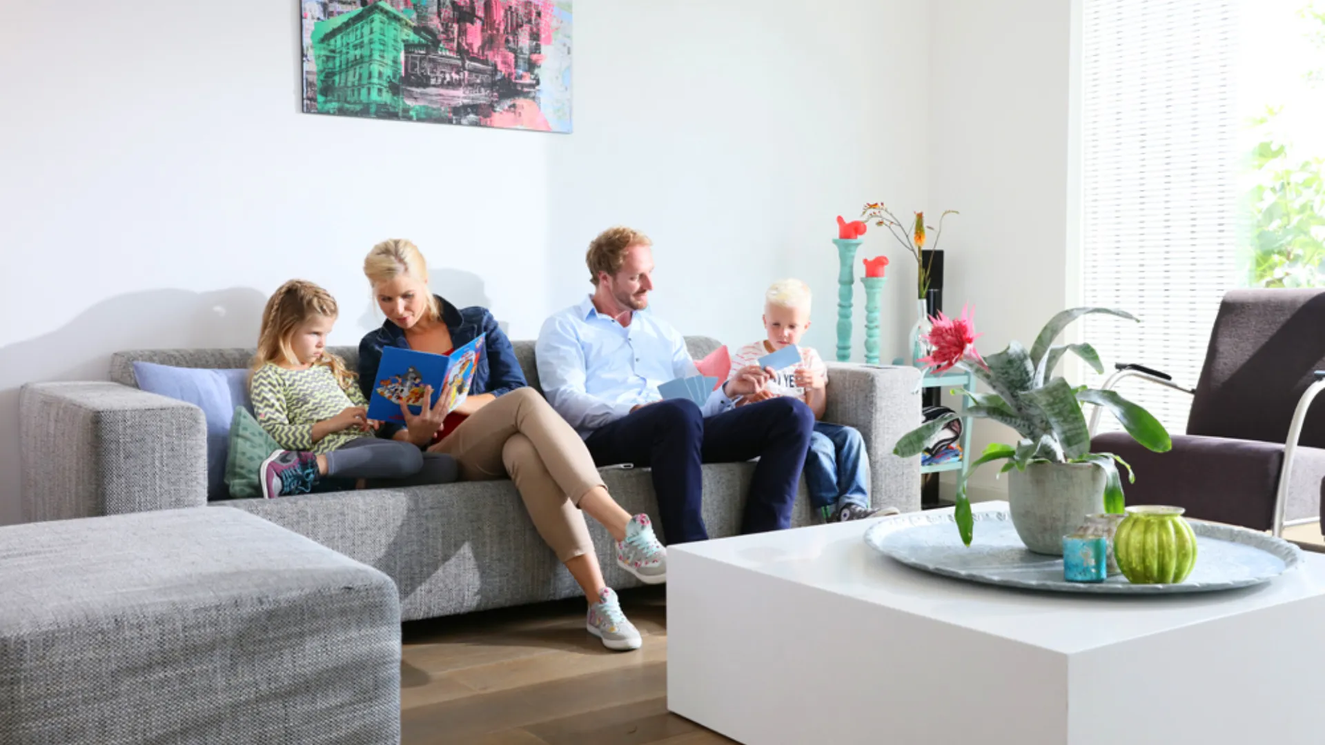 Gezin van vier zit op de bank met een boek