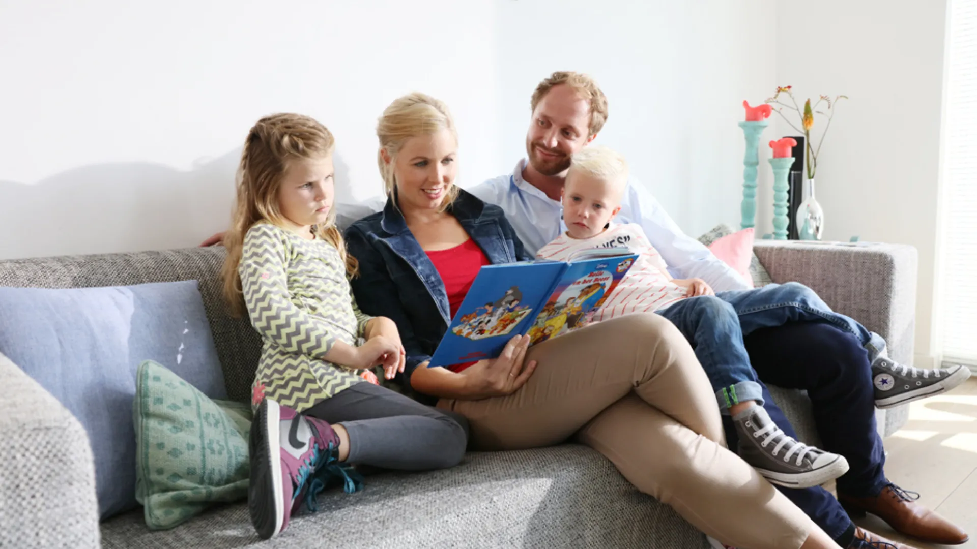 Gezin van vier zit op de bank met een boek