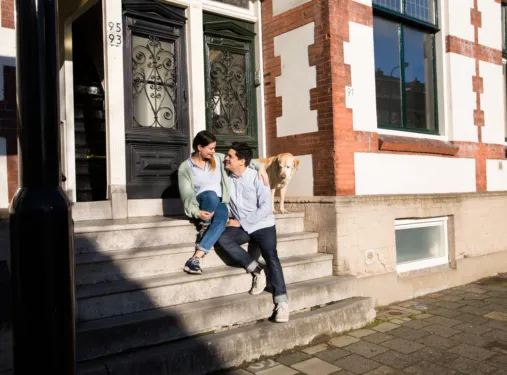 Twee personen zitten voor de deur op een trap