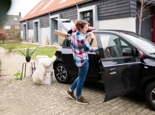 Persoon zet doos met spullen in auto