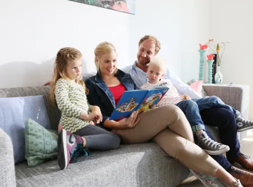 Gezin van vier zit op de bank met een boek