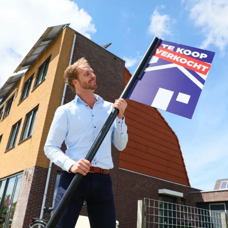 Persoon zet verkocht bord in de grond