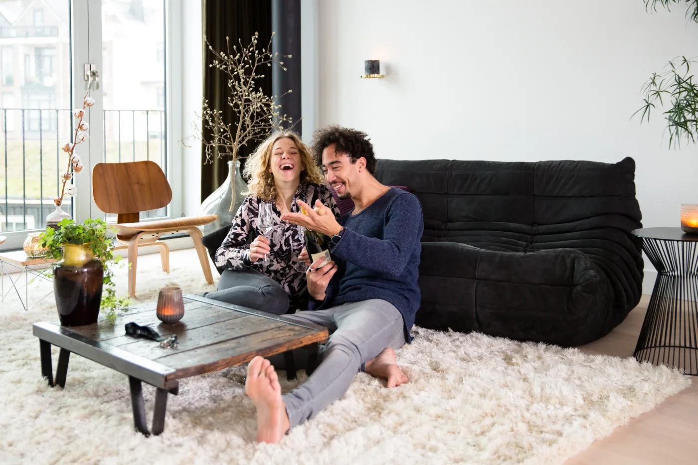 Personen zitten voor de bank op de grond en lachen samen