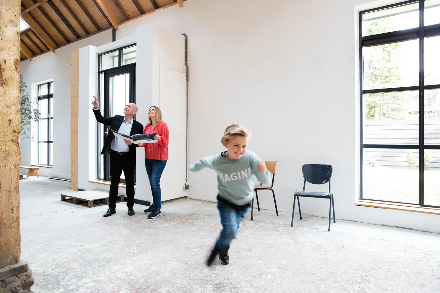 Twee personen bekijken het plafond en kind springt door de ruimte