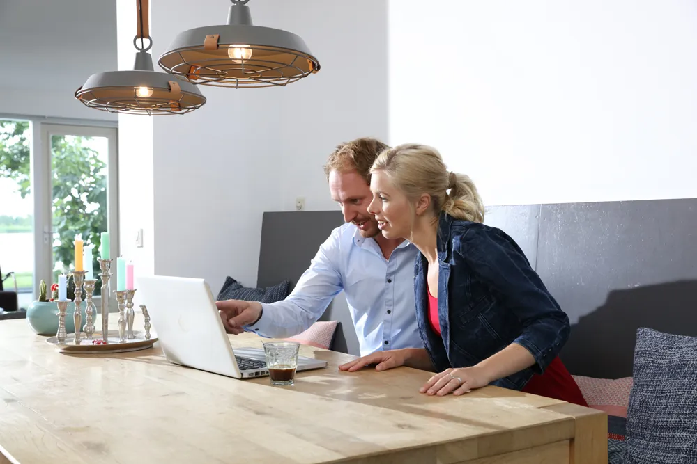 Twee personen zitten aan de keukentafel achter een laptop
