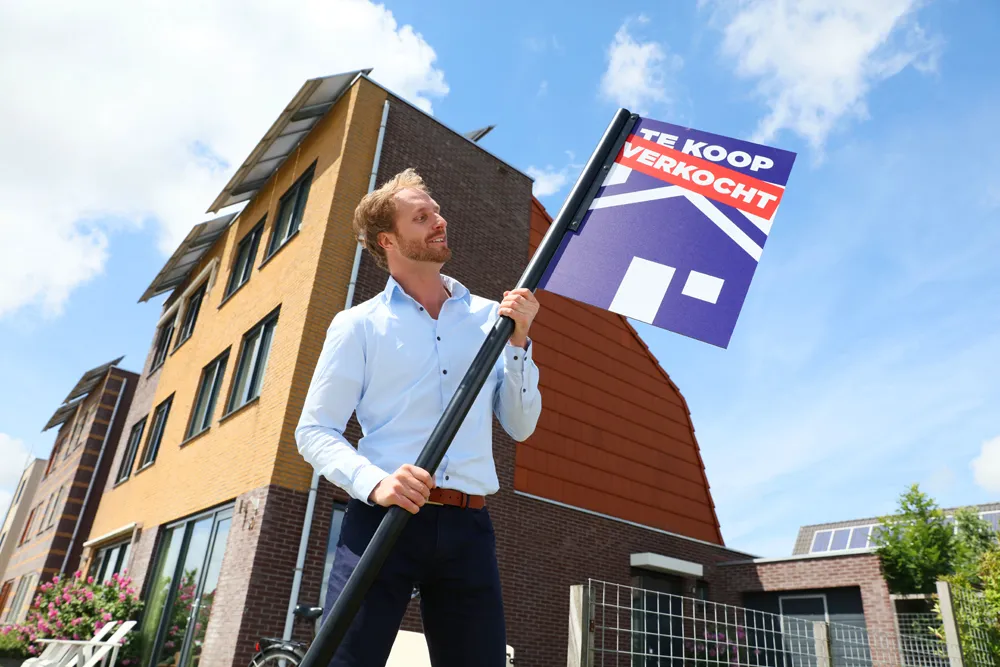 Persoon zet verkocht bord in de grond