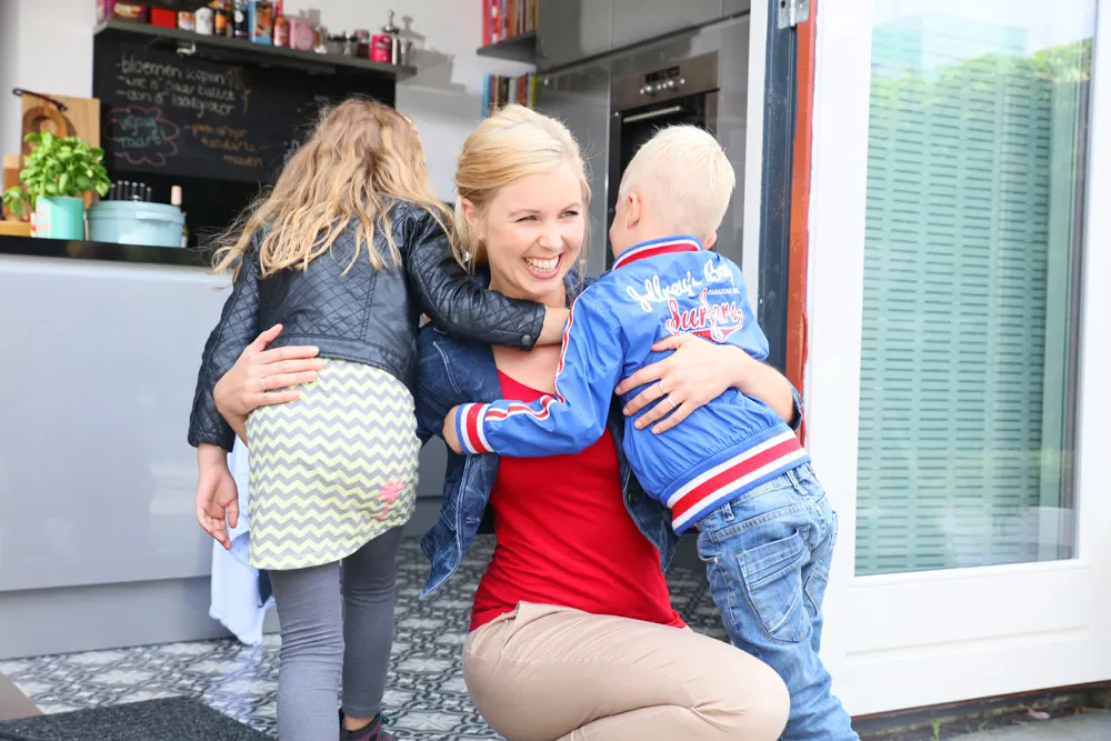 Persoon geeft twee kinderen een knuffel