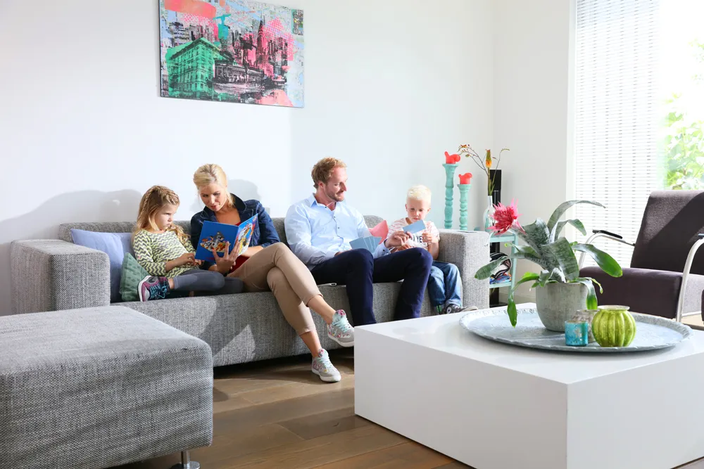 Gezin van vier zit op de bank met een boek