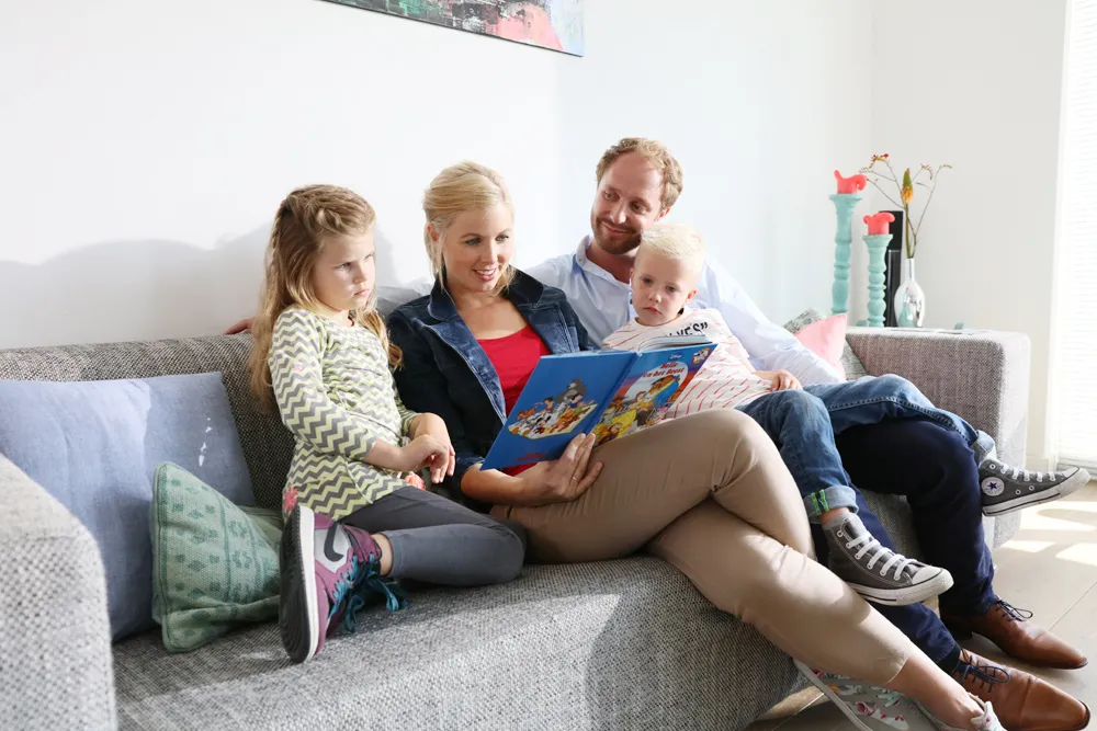 Gezin van vier zit op de bank met een boek