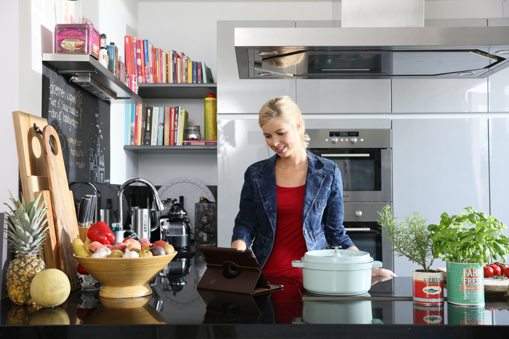Persoon staat in keuken op tablet te kijken